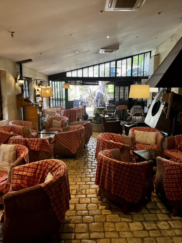 Ein geräumiger Hotellobby mit Reihen von Stühlen und Tischen, gepolsterte Sofas, Wandlampen, eine Deckenklimaanlage und Glasfenster an der Rückseite.