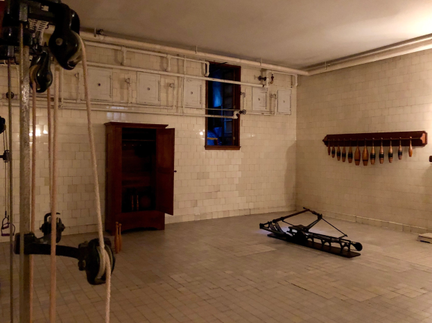 Ein unordentliches Zimmer im ehemaligen Gefängnis von St. Louis, Missouri, mit Seilen, Maschinen und anderem Equipment auf dem Boden, einem Schrank, einem Fenster und einer Deckenlampe im Hintergrund.