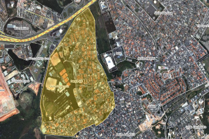 Luftaufnahme einer Stadt mit Gebäuden, Straßen und Grünflächen, überlagert mit einer Karte eines geplanten Baugebiets in der Mitte.