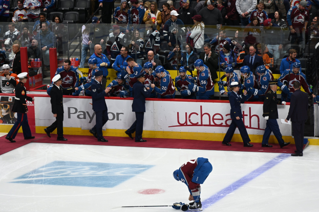 Eishockeyspieler auf dem Eis umgeben von Teamkollegen und Gegenspielern, mit Zuschauern im Hintergrund während eines Spiels von Colorado Avalanche gegen San Jose Sharks am 24. März 2015.
