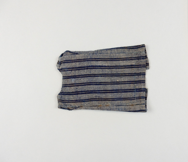 Ein Stofffetzen mit gleichmäßig verteilten blauen und weißen horizontalen Streifen, leicht zerknittert, auf einer weißen Oberfläche.