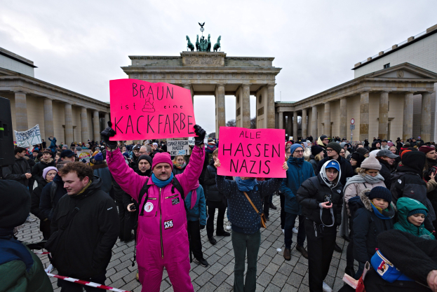 Eine Gruppe von Menschen protestiert vor dem Brandenburger Tor in Berlin und hält Schilder gegen die Anti-Nazi-Bewegung der deutschen Regierung.