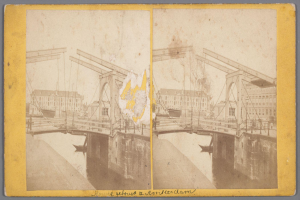 Ein altes Foto einer Brücke, die über ein Gewässer führt und im Hintergrund Gebäude zeigt, mit Anzeichen von Reparaturen und verstreuten Werkzeugen und Materialien.