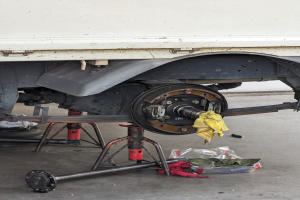 Ein gelber, mit einem Tuch bedeckter Lastwagen in einer Garage mit Werkzeugen und Gegenständen, die vor ihm auf dem Boden verstreut sind.