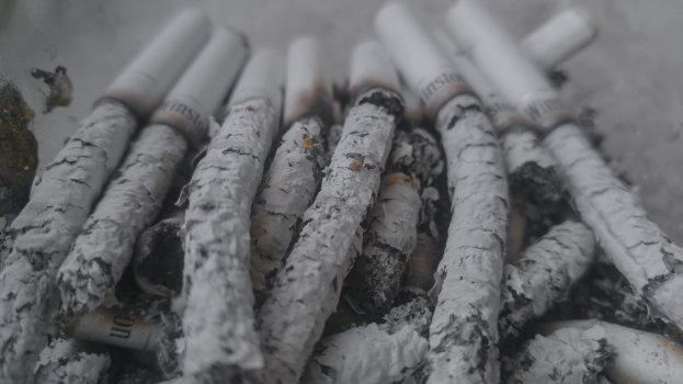 Ein Haufen aschfarbener Zigaretten auf einem Tisch.