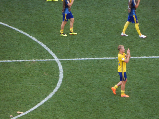 Mannengruppe in Fußballtrikots klatscht auf einem Fußballfeld.