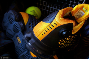 Ein Paar Schuhe und ein Ball befinden sich in der Mitte des Bildes, mit einem Zaun im Hintergrund.