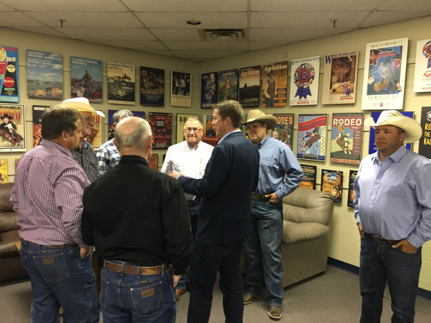 Eine Gruppe von Männern in einem Raum mit Sofas, Plakaten an den Wänden und Deckenleuchten, die sich unterhalten.