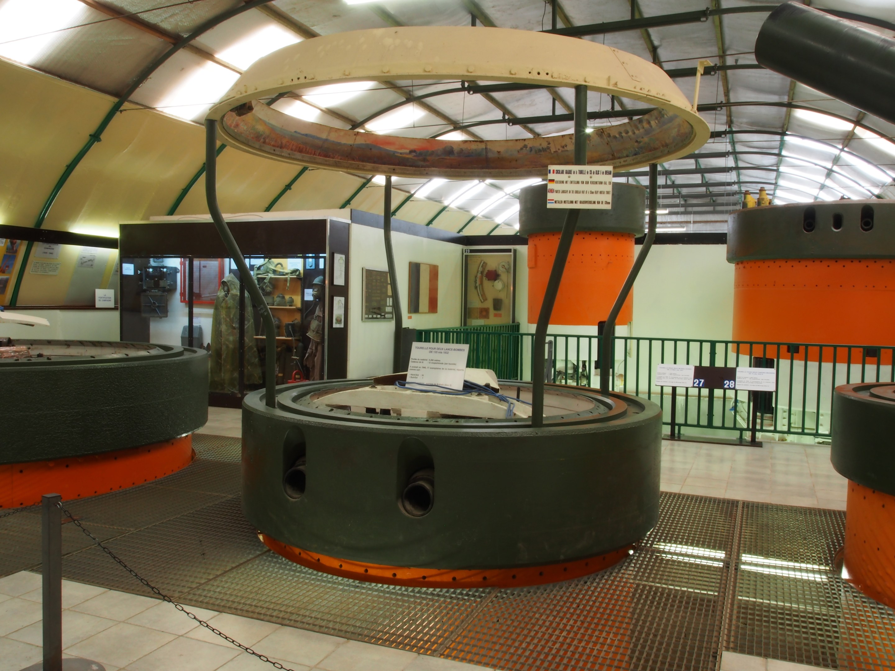 Ein großer industrieller Raum mit verschiedenen Maschinen, darunter ein Rotor, eine Kette, Stangen, Texttafeln, ein Zaun, eine Wand, eine Decke und Beleuchtung.