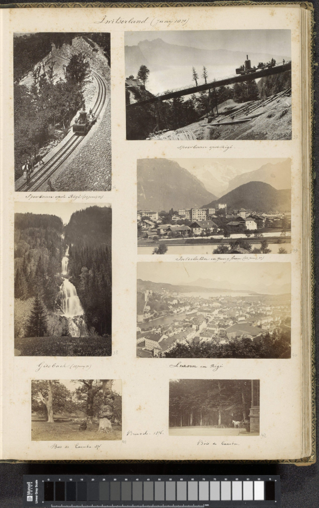 Ein aufgeschlagenes Buch mit Bildern von Bäumen, Gebäuden, Hügeln, einer Eisenbahn auf Schienen, einem Wasserfall und einem Himmel, mit Text am unteren Rand.