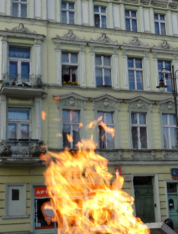 Großbrand vor einem Gebäude mit Fenstern, Türen, einer Straßenlaterne und einer Tafel mit Text.