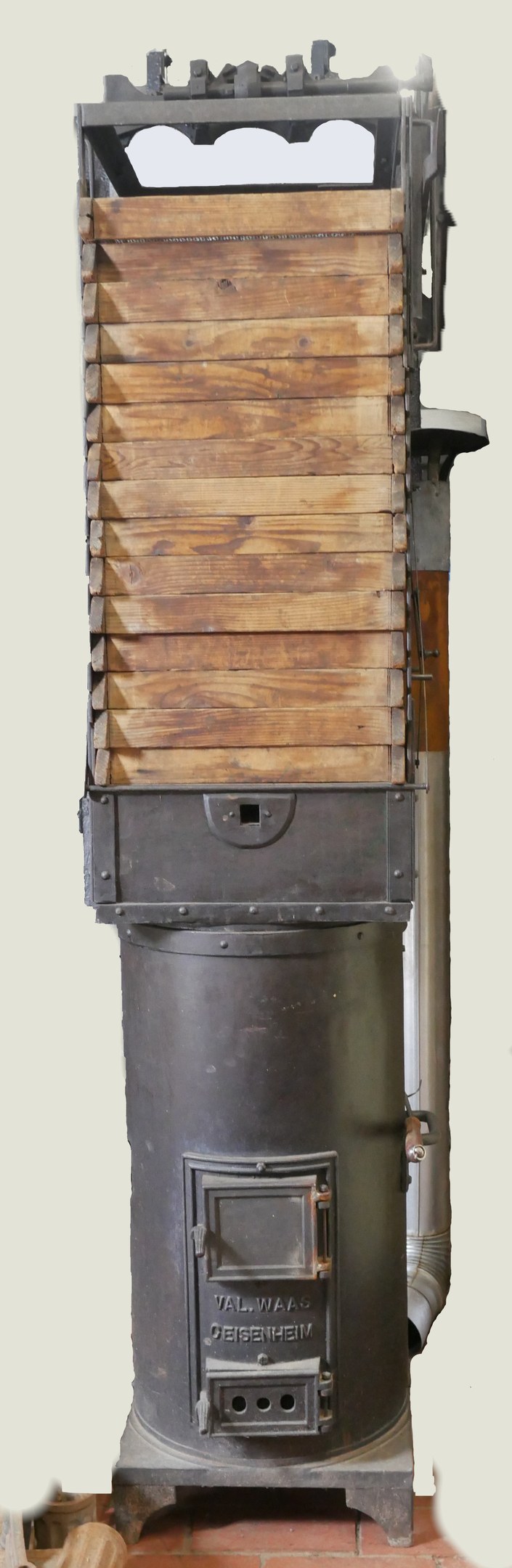 Altmodischer Holzofen mit Metall- und Holzkonstruktion, Schornstein, auf einem Ziegelboden an einer Wand.