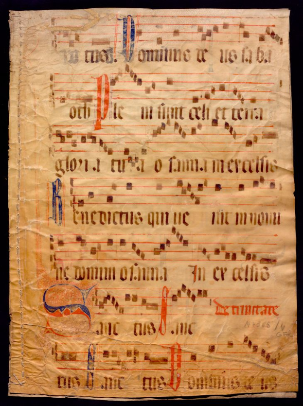 Ein illuminiertes Manuskript mit Musiknotation auf einem Blatt Papier vor dunklem Hintergrund, gefüllt mit Text und musikalischen Symbolen, die ein komplexes Design bilden.