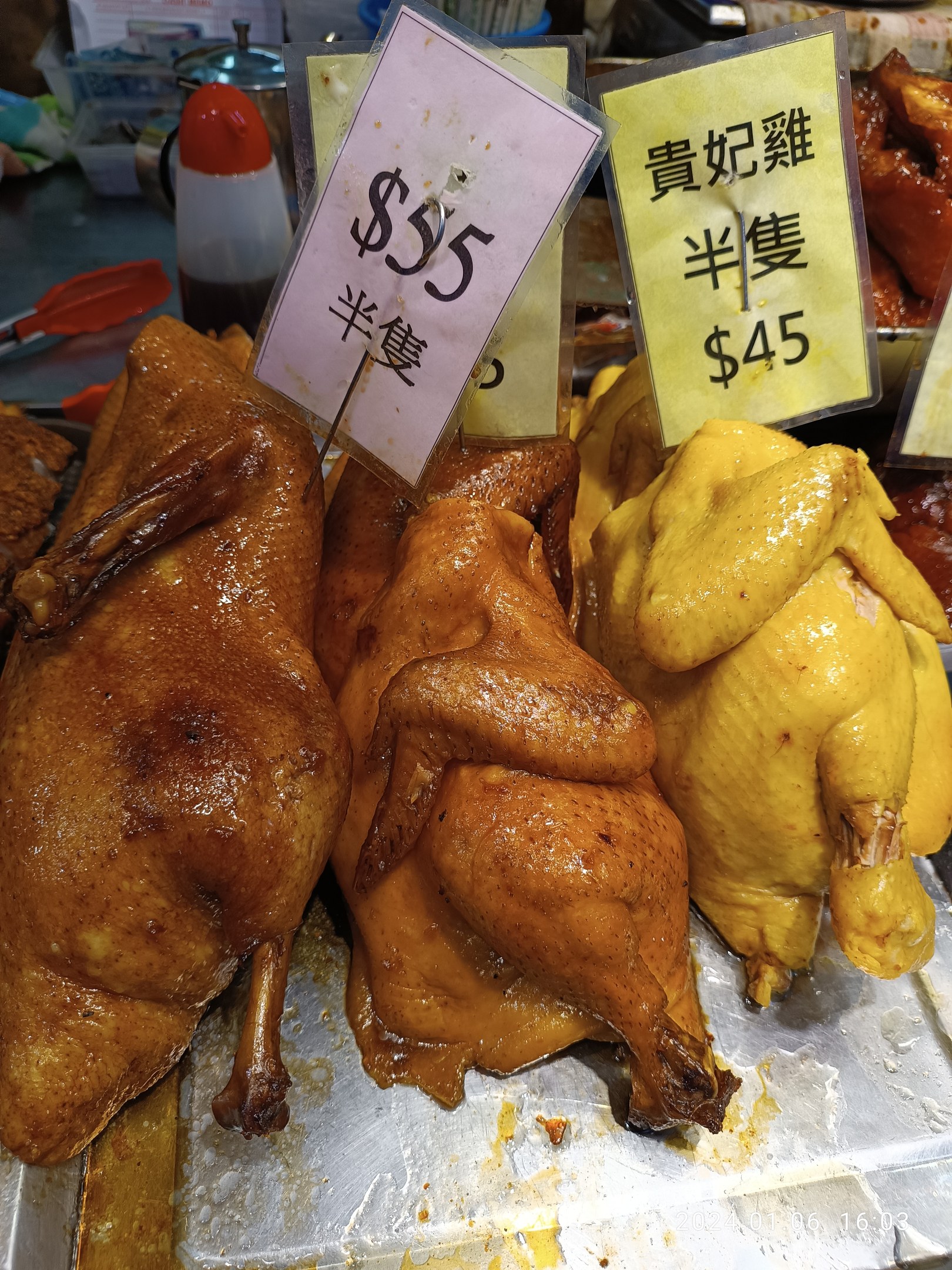 Eine Ansammlung von Hühner auf einem Metalltablett mit Preisschildern in einer Marktsituation.