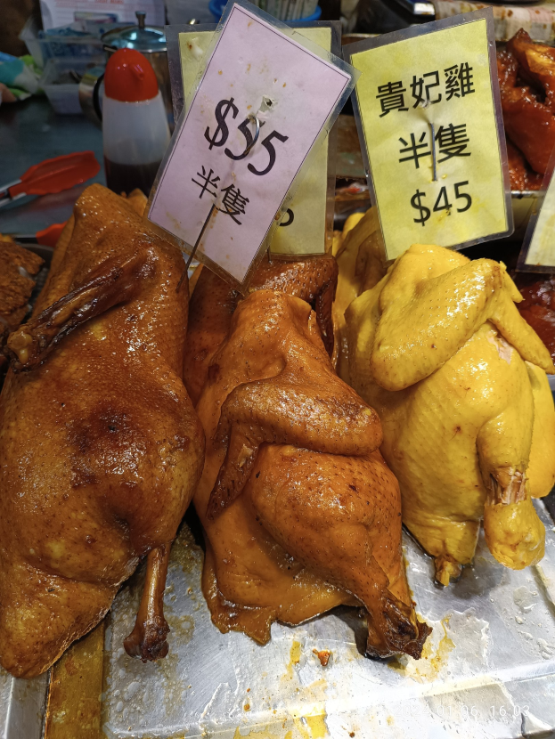 Eine Ansammlung von Hühner auf einem Metalltablett mit Preisschildern in einer Marktsituation.