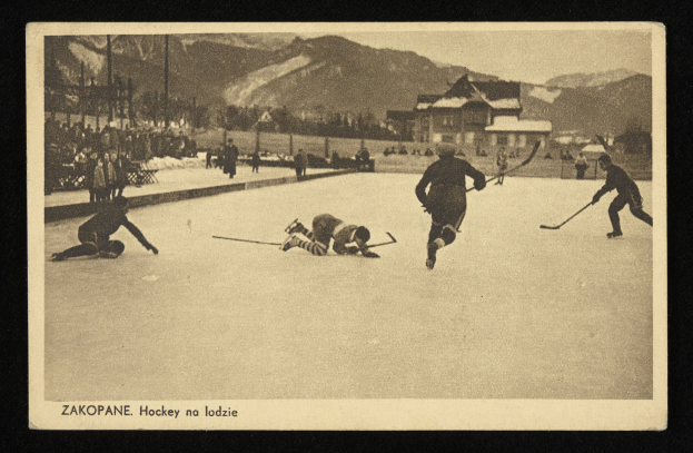 Schwarzes und weißes Foto von Menschen, die Hockey auf einem Eisplatz mit Gebäuden, Bäumen, Pfählen und Bergen im Hintergrund spielen, einschließlich Text unten.