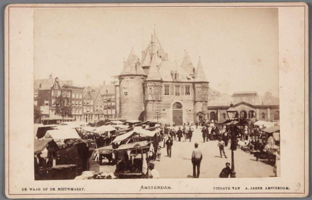 Schwarzes und weißes Foto eines belebten Amsterdamer Marktes mit Menschen, Ständen und Gebäuden im Hintergrund, mit Text unten.