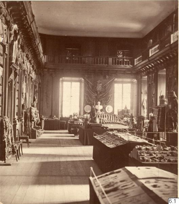 Schwarz-weiß-Foto eines Raums im Museum of Fine Arts, London, voller Tische, Stühle, Skulpturen an den Wänden, Fenstern mit Vorhängen und Geländern.