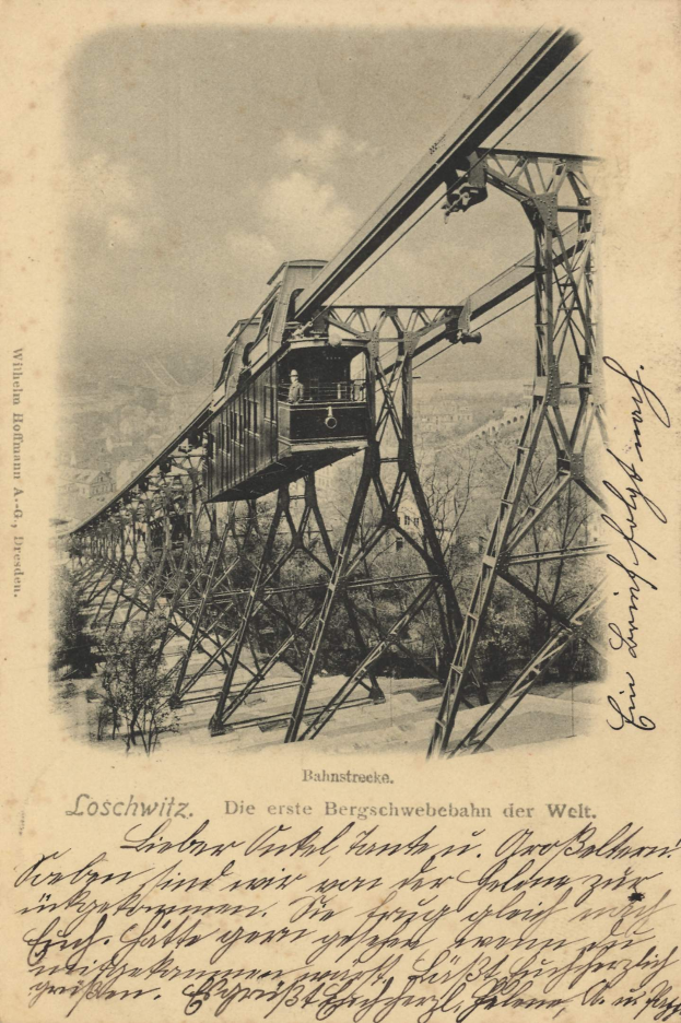 Ein altes Schwarz-Weiß-Foto einer Eisenbahnbrücke mit einem Kran, umgeben von Bäumen und einem bewölkten Himmel, mit Text unten lesbar "Bahnstrecka, die erste Eisenbahnbrücke in Deutschland".