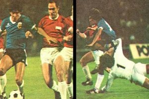 Eine Gruppe von Männern, die Fußball auf einem Feld spielen, mit einem Scoreboard im Hintergrund, ein Spieler tritt den Ball, während andere versuchen, die Kontrolle zu übernehmen.