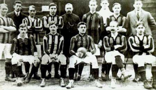 Ein Schwarz-Weiß-Foto einer Fußballmannschaft, die teilweise steht und teilweise sitzt, vor einer Wand, mit dem Text "Ballymena Football Club" unten.