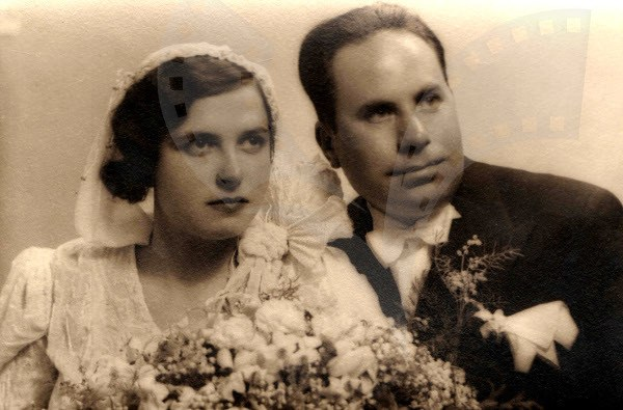 Ein Schwarz-Weiß-Foto eines Mannes und einer Frau an ihrem Hochzeitstag, die Frau in einem weißen Kleid mit einem Strauß Blumen, beide strahlend.