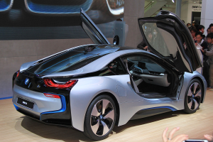 Ein silberner BMW i8-Konzeptwagen, der auf der Frankfurter Motor Show ausgestellt wird, umgeben von Menschen und einer Person mit einem Handy im Vordergrund.