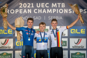 Drei medaillenreiche Männer auf einem Podium bei den 2021 UEC MTB Europameisterschaften, jeder hält einen Blumenstrauß.