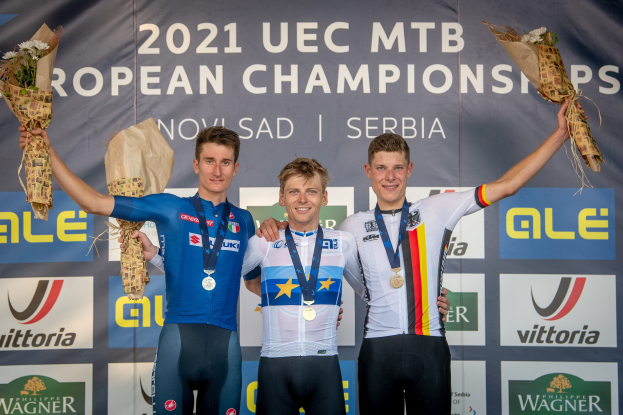 Drei medaillenreiche Männer auf einem Podium bei den 2021 UEC MTB Europameisterschaften, jeder hält einen Blumenstrauß.