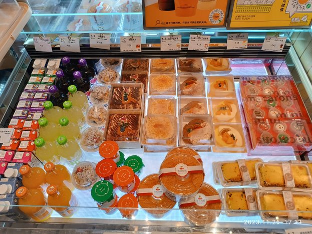 Ein Supermarktregal mit Flaschen, Schachteln und anderen Lebensmitteln mit Preisschildern auf der Scheibe.