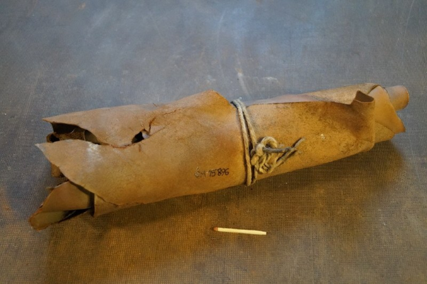 Papiertüte in Form einer Granate mit einer Zigarette daneben auf einem Tisch, mit einem Seil verschnürt.